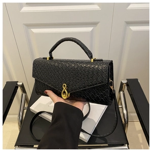 Detail of black textured handbag featuring elegant gold hardware and top handle design
