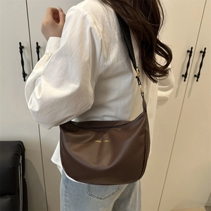 Sac fourre-tout marron café avec large bandoulière porté par un modèle, style épuré