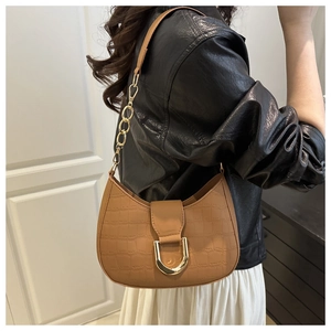 Detail of caramel brown croc-embossed half-moon bag with golden D-ring and chain strap