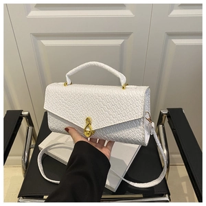 Detail of white crocodile embossed shoulder bag featuring a gold infinity metal buckle