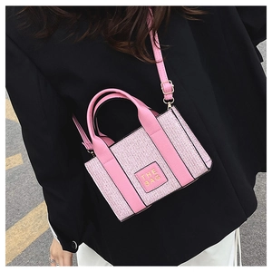 Detail of pink woven texture mini bag with 'THE BAG' patch and leather strap