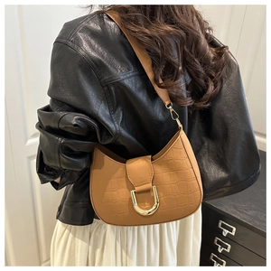 Detail of caramel crocodile embossed crescent bag with a gold metal buckle on shoulder