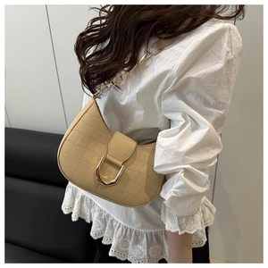 Close-up of beige crocodile embossed crescent bag featuring a gold U-shaped metal buckle