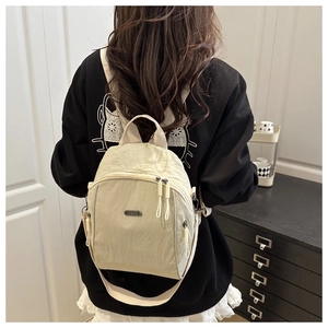Detail of off-white nylon backpack showing water-resistant fabric and metal logo plaque