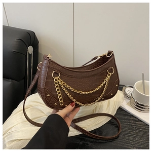 Close-up of brown crocodile texture crescent bag with gold chains and rivet details