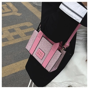Pink glitter small tote bag with The Bag patch shown styled with a black blazer