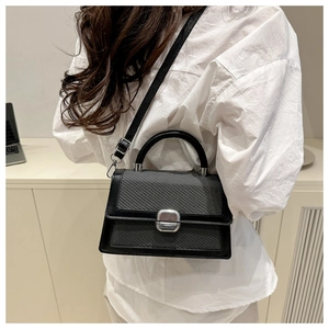 Detail of grey woven texture flap on shoulder bag with silver metal buckle and black handle