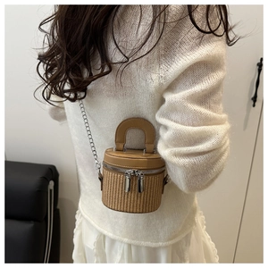 Mini straw bucket bag with leather handle and metal chain shown on model's back