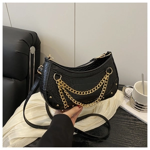 Detail of black crocodile texture crescent bag with gold chains and metallic studs decoration