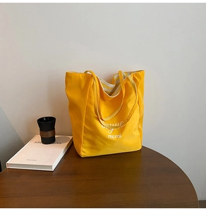 Detail view of the yellow canvas tote bag showing striped lining and soft texture