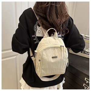 Detail of cream nylon backpack with crinkled texture and front zippered pocket