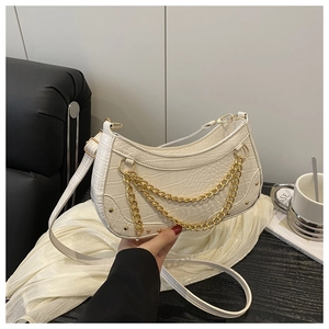 Close-up of white croc-embossed leather crescent bag with gold chain and rivet details