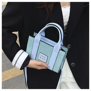 Detail of light blue woven texture mini tote bag with THE BAG label and leather trim