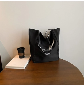 Detail of black striped canvas tote bag with white mcroi lettering on a wooden table