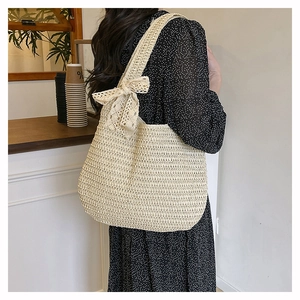 Sac fourre-tout en paille avec nœud en dentelle blanche porté par un mannequin