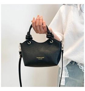 Detail of black lychee texture bucket bag with decorative handle knot and gold hardware