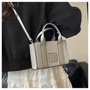 Detail of silver sequin tote bag with the bag text logo and slim crossbody strap