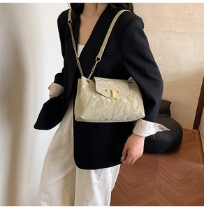 Dettaglio borsa a tracolla in pelle beige testurizzata con fibbia in metallo dorato a forma di T