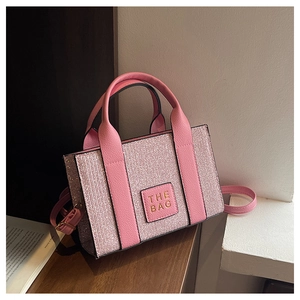 Detail of pink glitter tote bag with leather top handles and adjustable shoulder strap