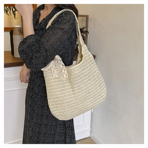 Close-up of beige woven hobo shoulder bag featuring a decorative lace bow detail
