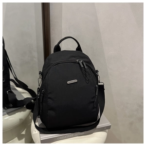 Detail showing the multi-layer zippers and metallic logo on black nylon backpack