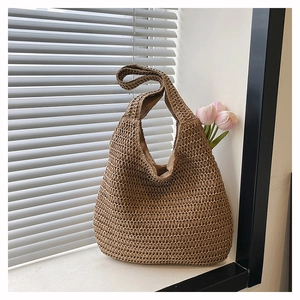 Detailed close-up of a woven straw hobo bag with beige lining on a bright windowsill