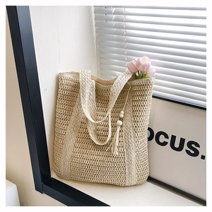 Detail of beige woven straw tote bag with decorative wooden bead tassel and tulips