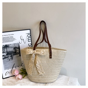 Détail du sac seau tissé crème avec nœud en dentelle et fines bandoulières en cuir