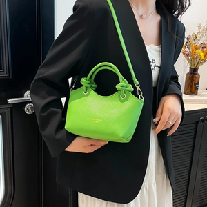 Vibrant green pebble leather mini bucket bag with knotted handles and crossbody strap