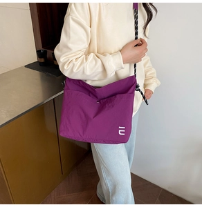 Détail de la sacoche en nylon violet avec bandoulière tissée noire et blanche
