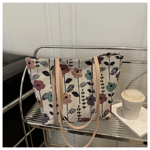 Détail du sac cabas jacquard à fleurs avec anses en cuir sur étagère chic