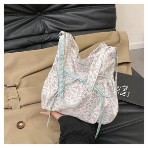 Detail of floral tote bag featuring a light blue checkered bow and matching handles