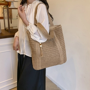 Handwoven straw tote bag with beaded tassels on a model for a chic spring look
