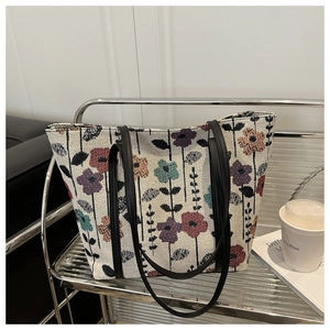 Gros plan du sac cabas en jacquard floral avec fines anses en cuir noir sur un chariot