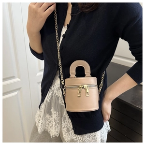 Détail du sac seau en cuir beige avec fermetures éclair dorées et bandoulière chaîne