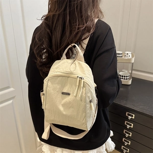 Minimalist beige nylon backpack with pleated texture and multi-pocket design for women