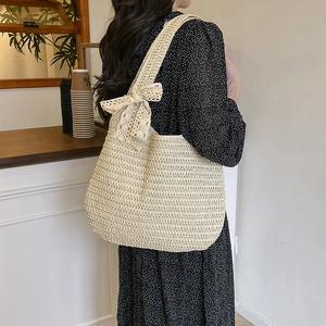 Chic beige woven tote bag with wide lace bow accent and spacious crescent-shaped design