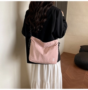 Gros plan détaillé du sac à bandoulière en nylon rose avec texture et logo discret