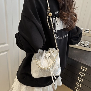 Elegant white lace bucket bag with pearl handle and gold chain strap in minimalist style