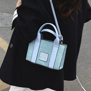 Light blue textured crossbody small square bag with gold The Bag lettering detail