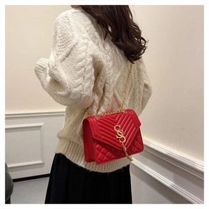 Red quilted leather square bag with gold chain strap shown on a model in knitwear