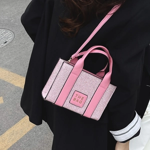 Pink tweed crossbody square bag with The Bag leather patch and adjustable shoulder strap
