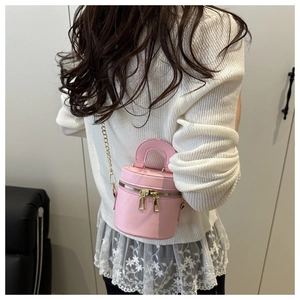 Détail d'un mini sac seau rose clair avec fermetures éclair dorées et bandoulière chaîne