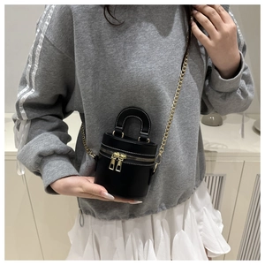 Détail du mini sac cylindrique noir avec surpiqûres blanches et chaîne dorée