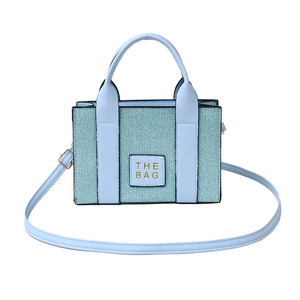 Light blue woven texture tote bag with THE BAG label and golden hardware on white background