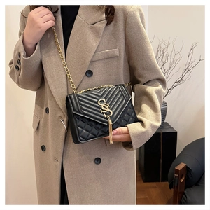Close-up of black quilted leather crossbody bag with gold hardware and tassel detail