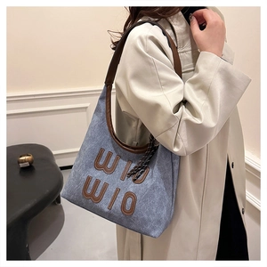 Détail du sac cabas en denim bleu avec anses en cuir marron et lettres WIO WIO