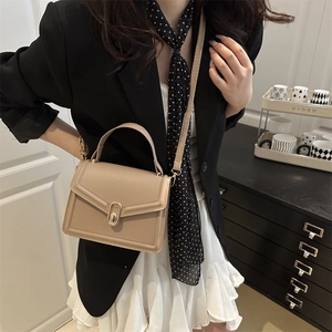 Beige rectangular crossbody bag with gold buckle shown on shoulder for a stylish look