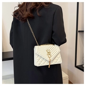Detail of white quilted leather bag with golden double S logo and tassel fringe