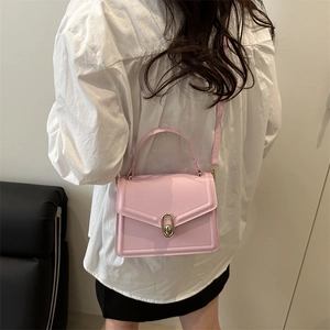 Minimalist light pink leather crossbody bag with gold hardware shown on a model